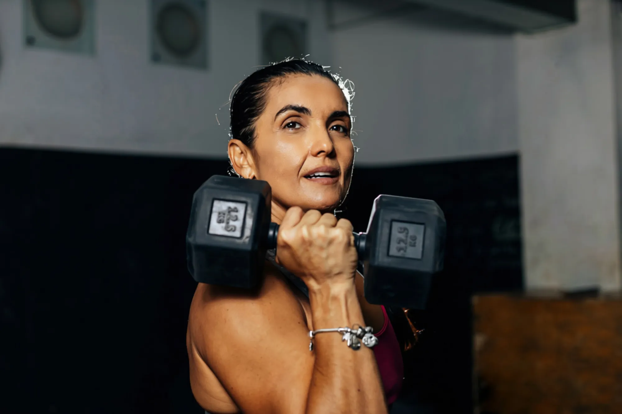 Woman in her fifties lifting dumbbells in a gym
